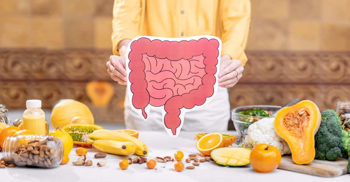 Picture of person holding up a cartoon version of our intestines over a table full of healing foods like bananas, papaya, squash, almonds, and broccoli.